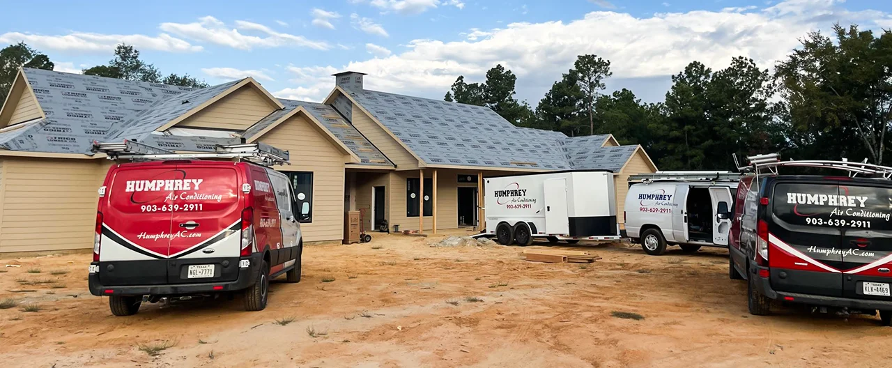 Humphrey AC trucks outside a new home construction in Hughes Springs.