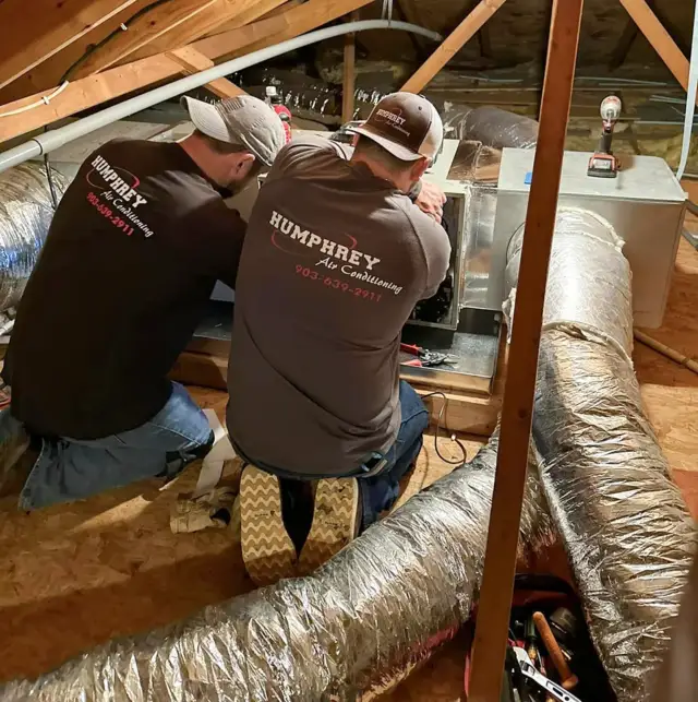 Technicians working on an attic AC unit