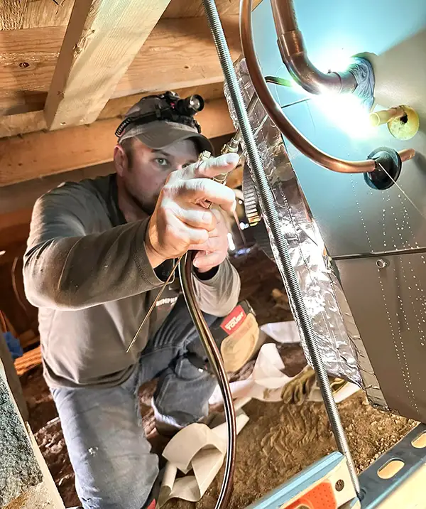 A Humphrey Air Conditioning tech works on a customer's HVAC in the attic