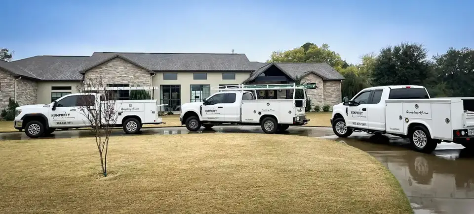The fleet of Humphrey Air Conditioning repair vehicles outside a customer's Hughes Springs home.