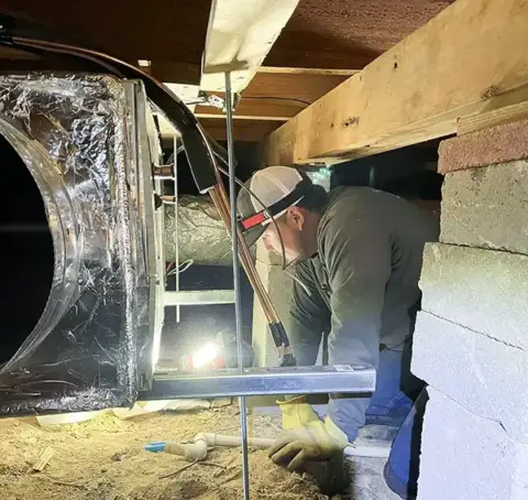 Humphrey AC repair tech under a home in crawl space